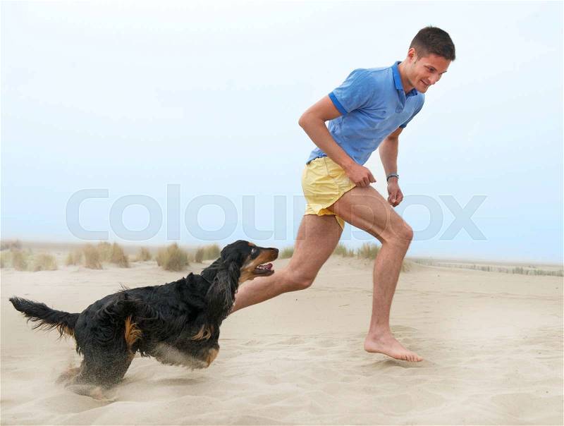 Man playing with his dog on the beach, stock photo