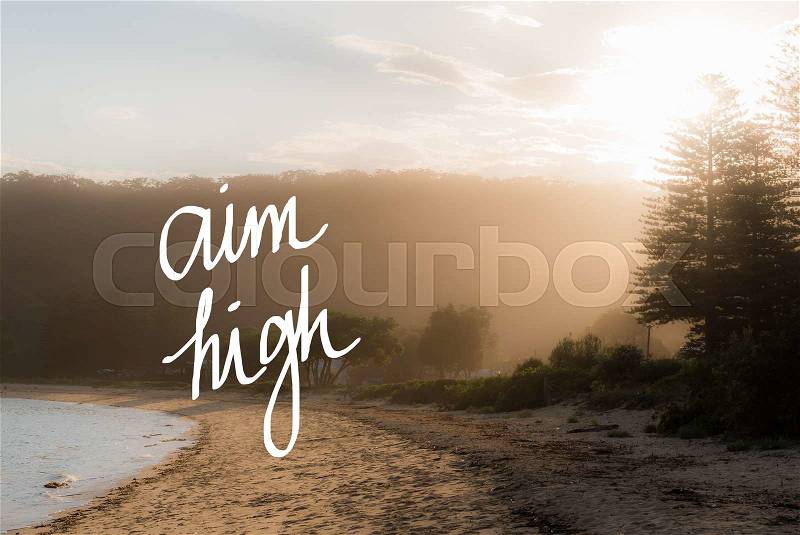 Aim High message. Handwritten motivational text over sunset calm sunny beach background with vintage filter applied, stock photo