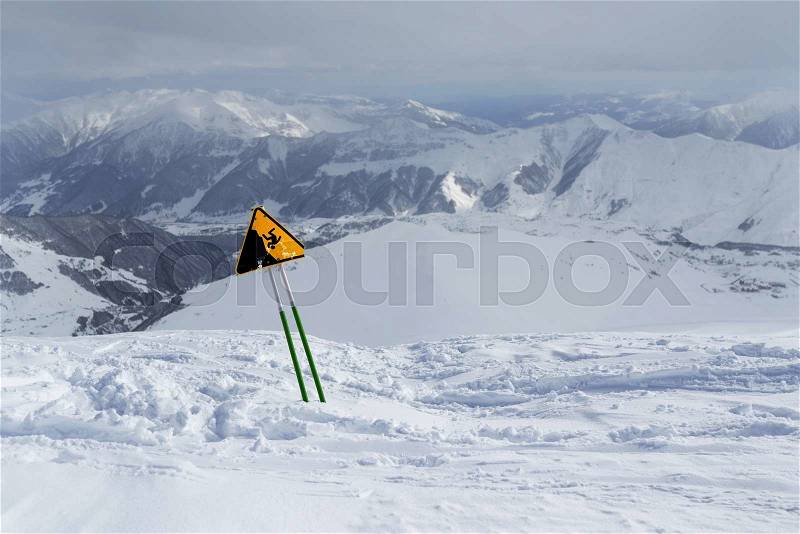 Label warning of a sharp cliff, standing in the snowy mountains, stock photo