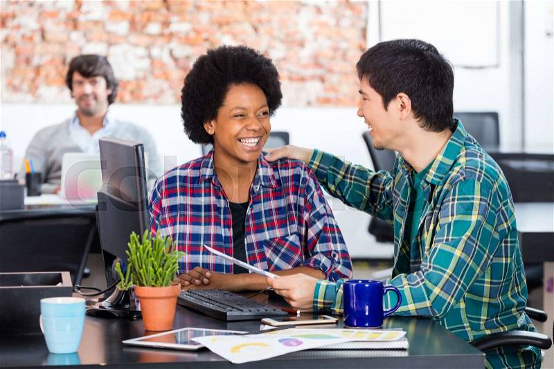 Two colleagues african american woman asian man diverse mix race talking discussing sitting office desk business people working casual wear, stock photo