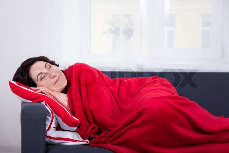 Happy mature woman sleeping on sofa at home, stock photo