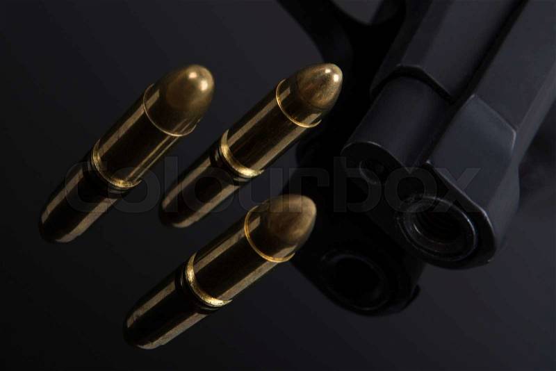 Gold bullets and gun on black background, stock photo