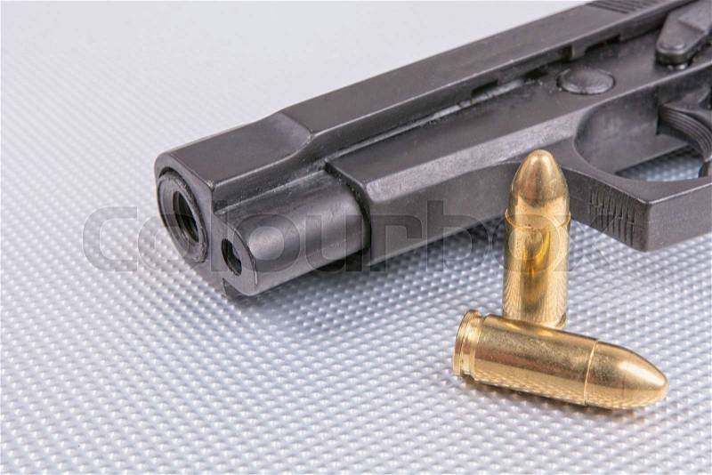 Gold bullets and gun on aluminium background, stock photo