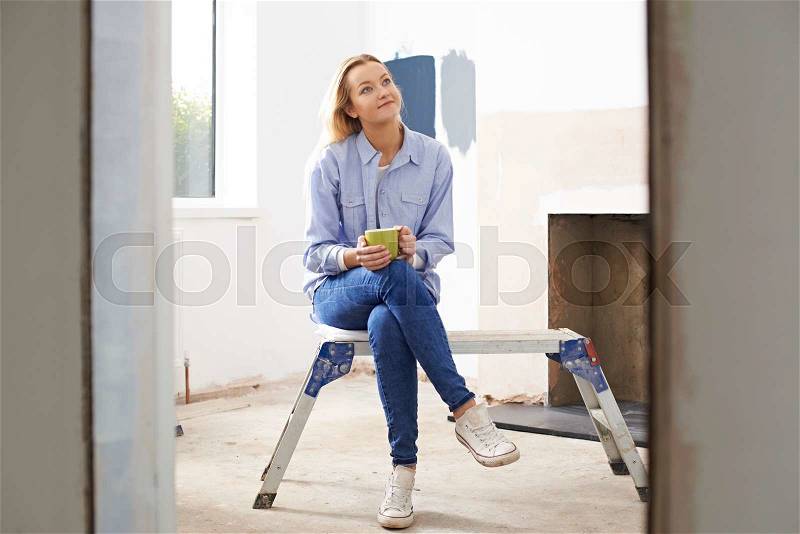 Woman Sitting In Property Being Renovated, stock photo
