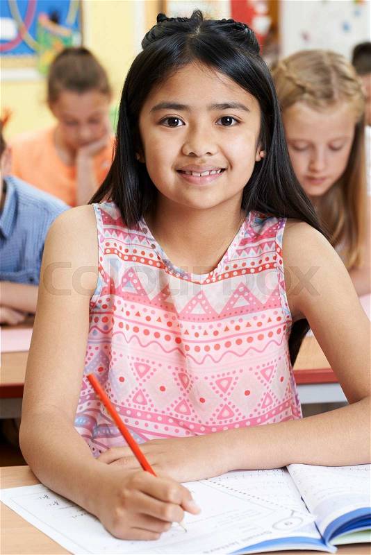 Female Elementary School Pupil Working At Desk, stock photo