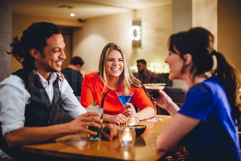 Group of friends enjoying cocktails in a restaurant, stock photo