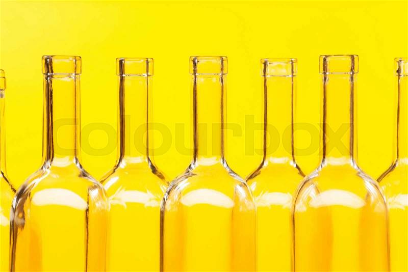 Close-up picture of bottle necks with patch of lights against the yellow background, stock photo