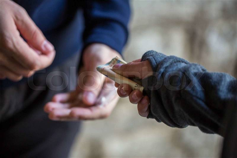 Drug trafficking, crime, addiction and sale concept - close up of addict with money buying dose from dealer on street, stock photo
