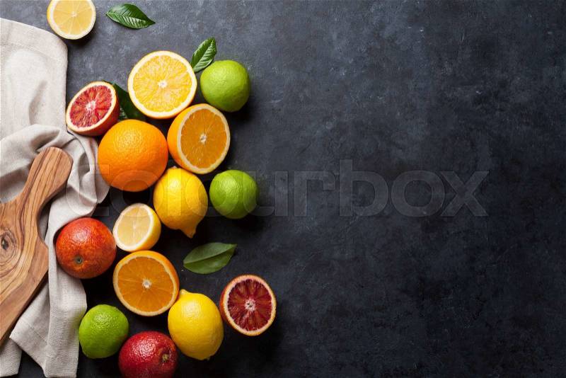 Fresh ripe citruses. Lemons, limes and oranges on dark stone background. Top view with copy space, stock photo