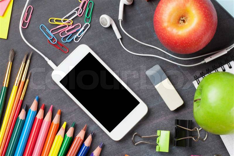 School and office supplies, smartphone and apples on blackboard background. Top view with copy space, stock photo