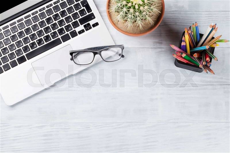 Desk table with laptop, glasses and pencils on wooden table. Workplace. Top view with copy space, stock photo