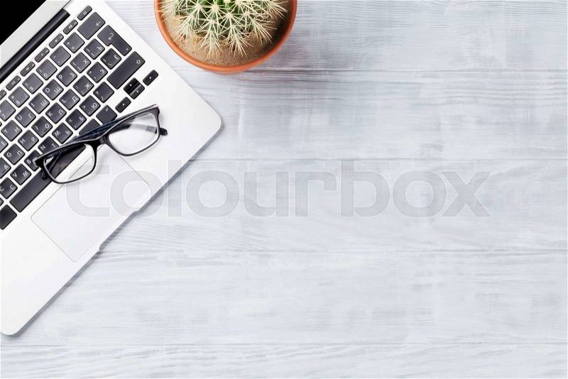 Desk table with laptop, glasses and cactus plant on wooden table. Workplace. Top view with copy space, stock photo