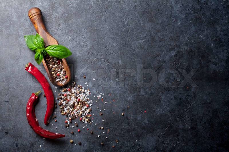 Pepper and salt spices, basil herb and chili pepper. Red, white and black peppercorn. On dark stone table. Top view with copy space, stock photo