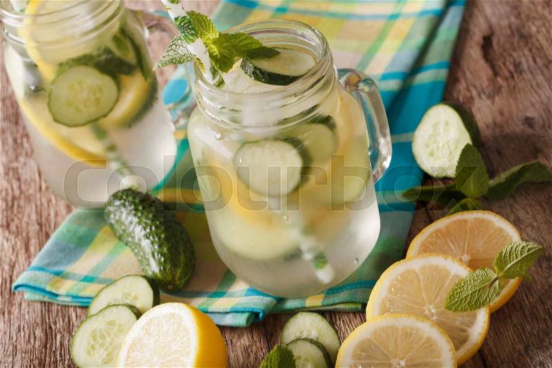 Cold water with cucumber, lemon, ice and mint close up in a glass jar on the table. horizontal , stock photo