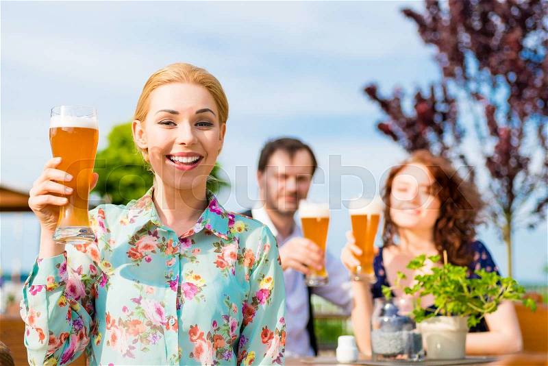 Woman drinking with friends in beer garden, stock photo