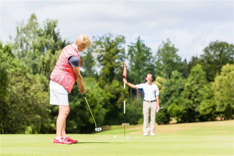 Senior woman practicing with golf pro , stock photo