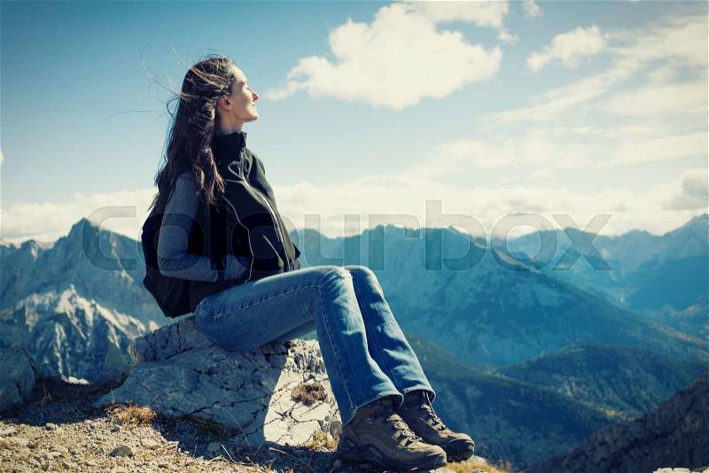 Woman on mountain hike having rest sitting on rock looking into the valley, stock photo
