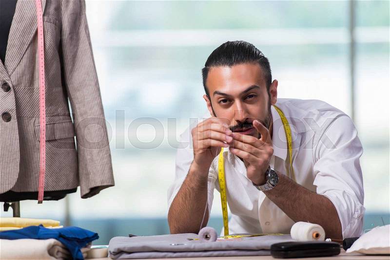 Young tailor working on new clothing design, stock photo