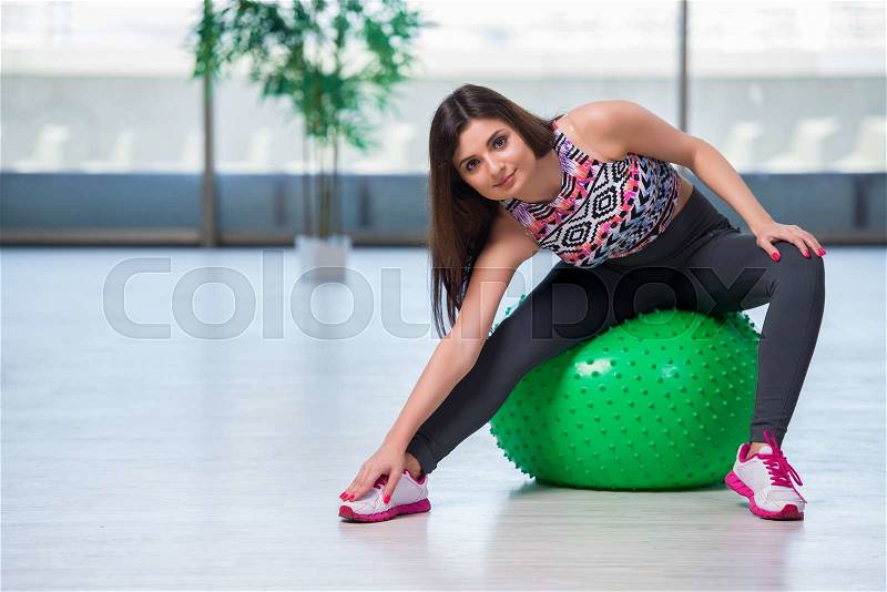 Young woman exercising with swiss ball in health concept, stock photo