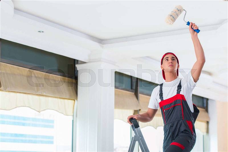 Young painter painting the ceiling in construction concept, stock photo
