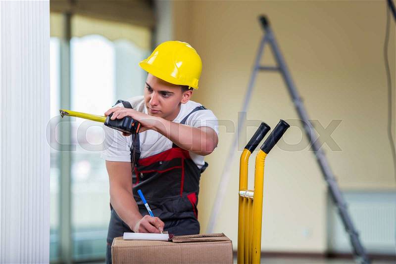 Delivery man taking dimensions with tape measure, stock photo