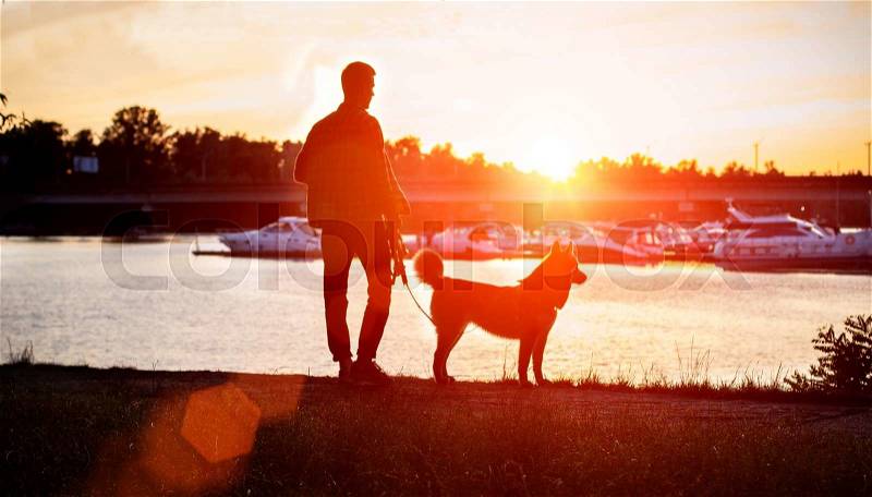 The guy with the dog watching the sunset on the dock. Ukraine, stock photo