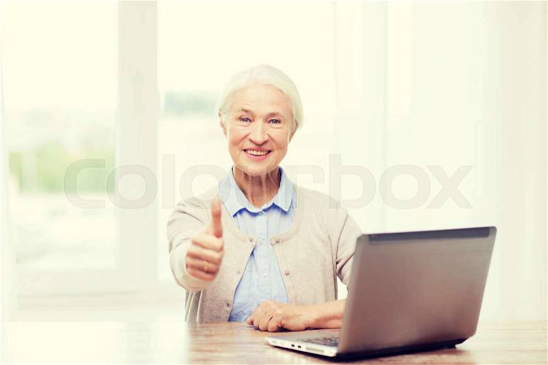 Technology, age and people concept - happy senior woman with laptop computer at home showing thumbs up gesture, stock photo