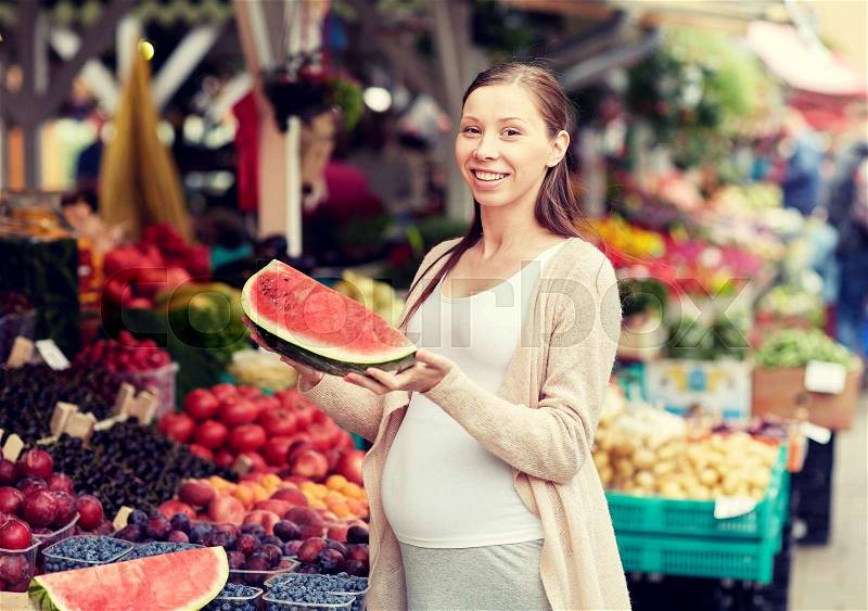 Sale, shopping, food, pregnancy and people concept - happy pregnant woman choosing watermelon at street market, stock photo