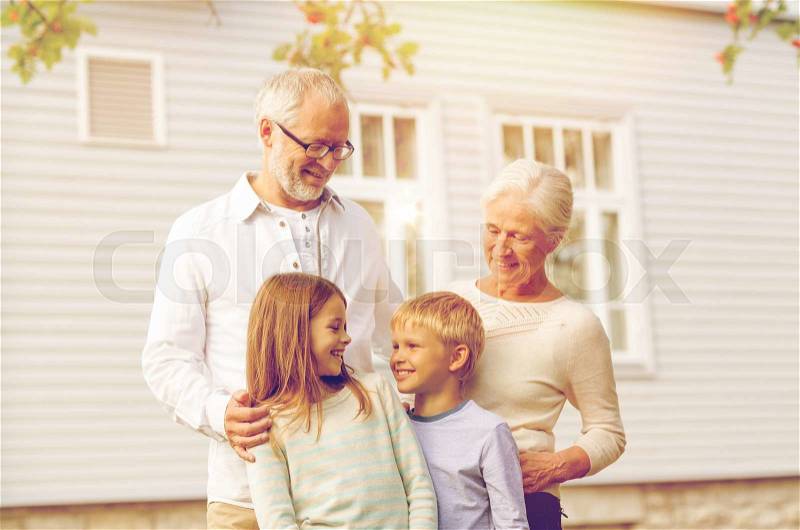 Family, happiness, generation, home and people concept - happy family standing in front of house outdoors, stock photo