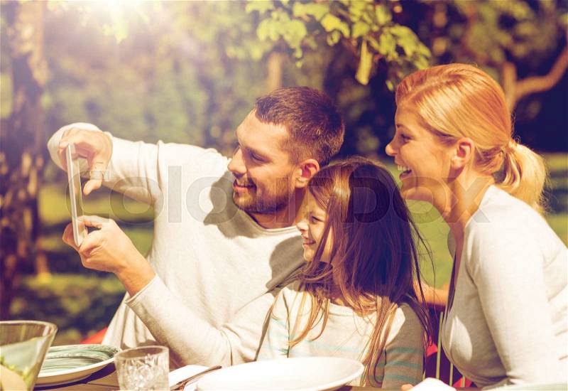 Family, happiness, generation, home and people concept - happy family sitting at table and taking selfie with tablet pc computer outdoors, stock photo