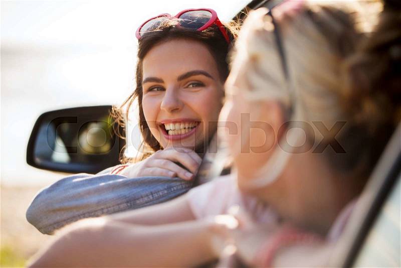 Summer vacation, holidays, travel, road trip and people concept - happy teenage girls or young women in car at seaside, stock photo