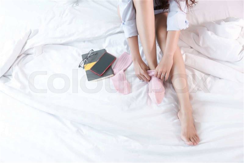 Young Asian woman sitting on a bed wearing socks. Top view. cool tone, low contrast, stock photo