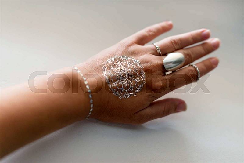 Woman hand with silver jewelry and flash tattooes in indian style. Summer beach fashion. Selective focus, stock photo
