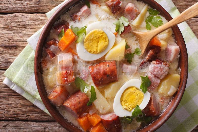 Delicious Polish soup Zurek with sausage and eggs in a bowl close-up. Horizontal view from above , stock photo