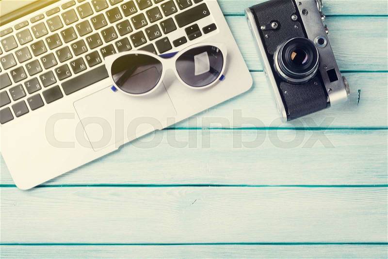 Desk table with laptop and camera on wooden table with sun beam. Workplace. Top view with copy space, stock photo