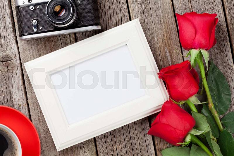 Valentines day roses, photo frame, retro camera and coffee cup over wooden background, stock photo