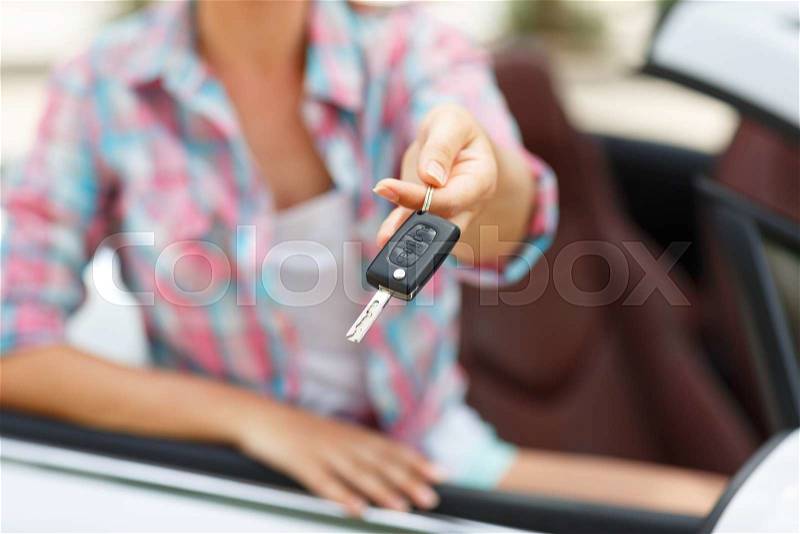 Young pretty woman standing near convertible with keys in hand - concept of buying a used car or a rental car, stock photo