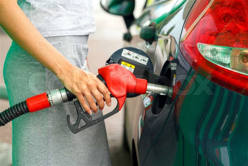 Woman fills petrol into the car at a gas station, stock photo