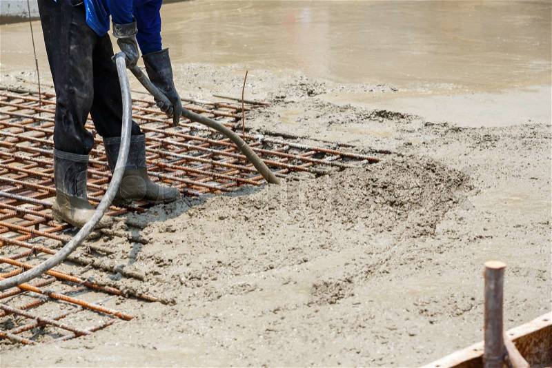 Close up worker using concrete vibrator to eliminate voids, increases concrete density and strength, stock photo