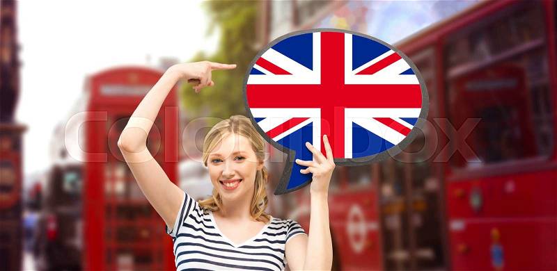 Foreign language, english, travel, people and communication concept - smiling woman holding text bubble of british flag and pointing finger over london city street background, stock photo