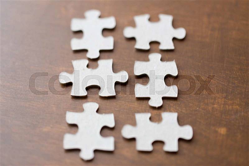 Business and connection concept - close up of puzzle pieces on wooden surface, stock photo