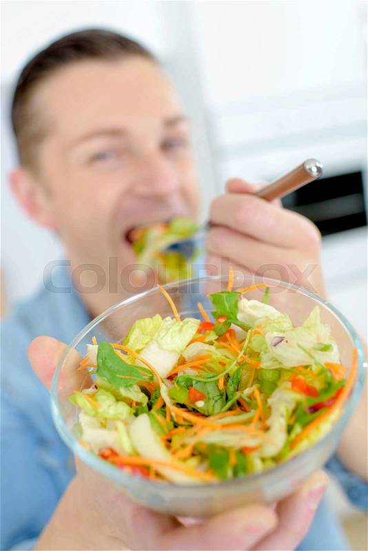 Man eating salad, showing bowl, stock photo