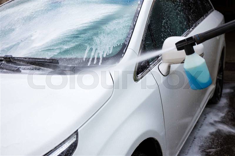 Car wash with high pressure water and blue washing liquid, stock photo