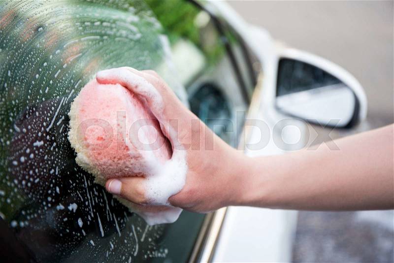 Handle car wash concept - male hand washing car window with sponge, stock photo