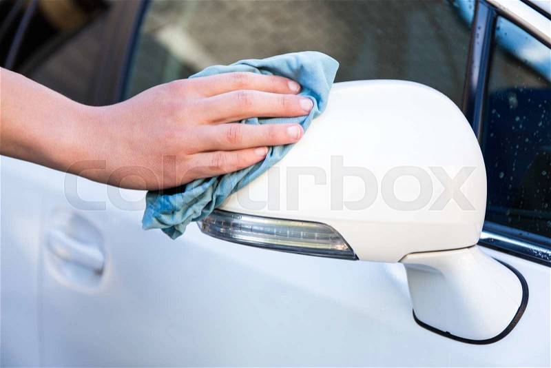 Male hand with blue microfiber cloth cleaning car mirror, stock photo