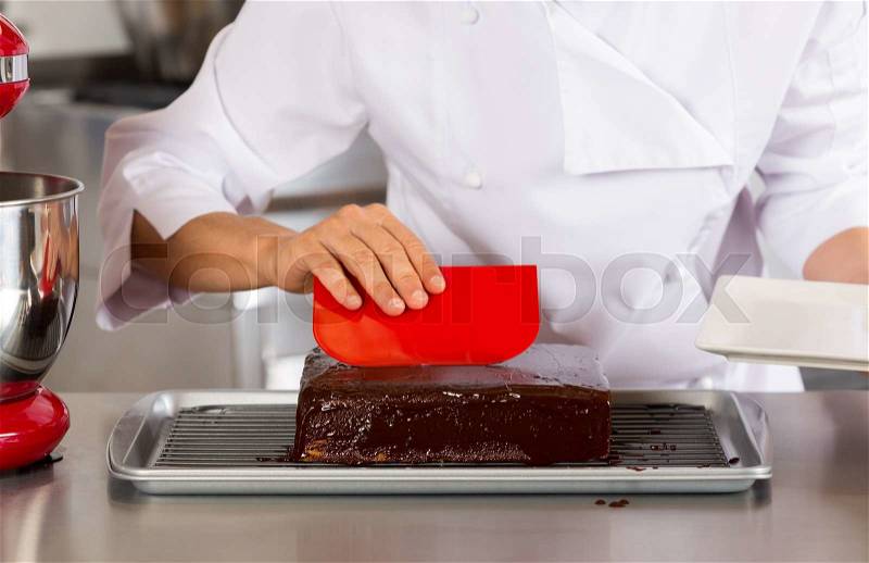 Pastry chef in the kitchen decorating a cake of chocolate, stock photo