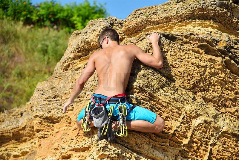 Extreme man climbing up on yellow rock, stock photo