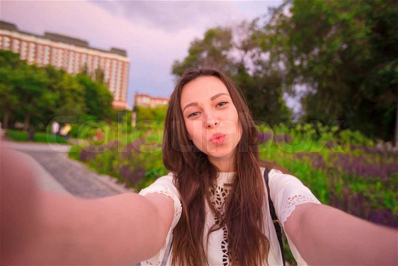 Young girl making video selfie and having fun in the park. Lifestyle selfie portrait of young positive woman having fun and taking selfie. Concept fun with new trends and technology, stock photo