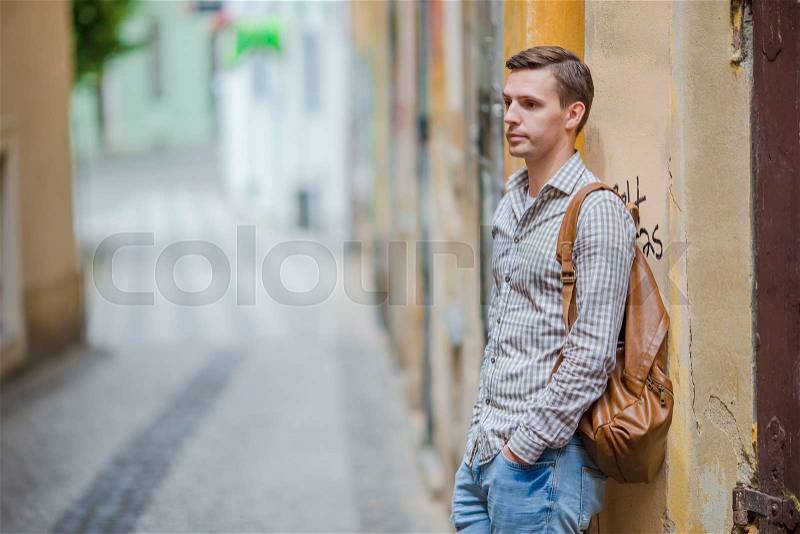 Caucasian tourist walking along the deserted streets of Europe. Young urban boy on vacation exploring european city, stock photo