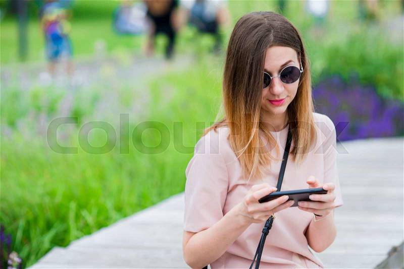 Tourist girl sending messgae by smartphone on summer holidays. Young attractive woman with mobile phone outdoors enjoying holidays travel destination in tourism and exploring concept, stock photo